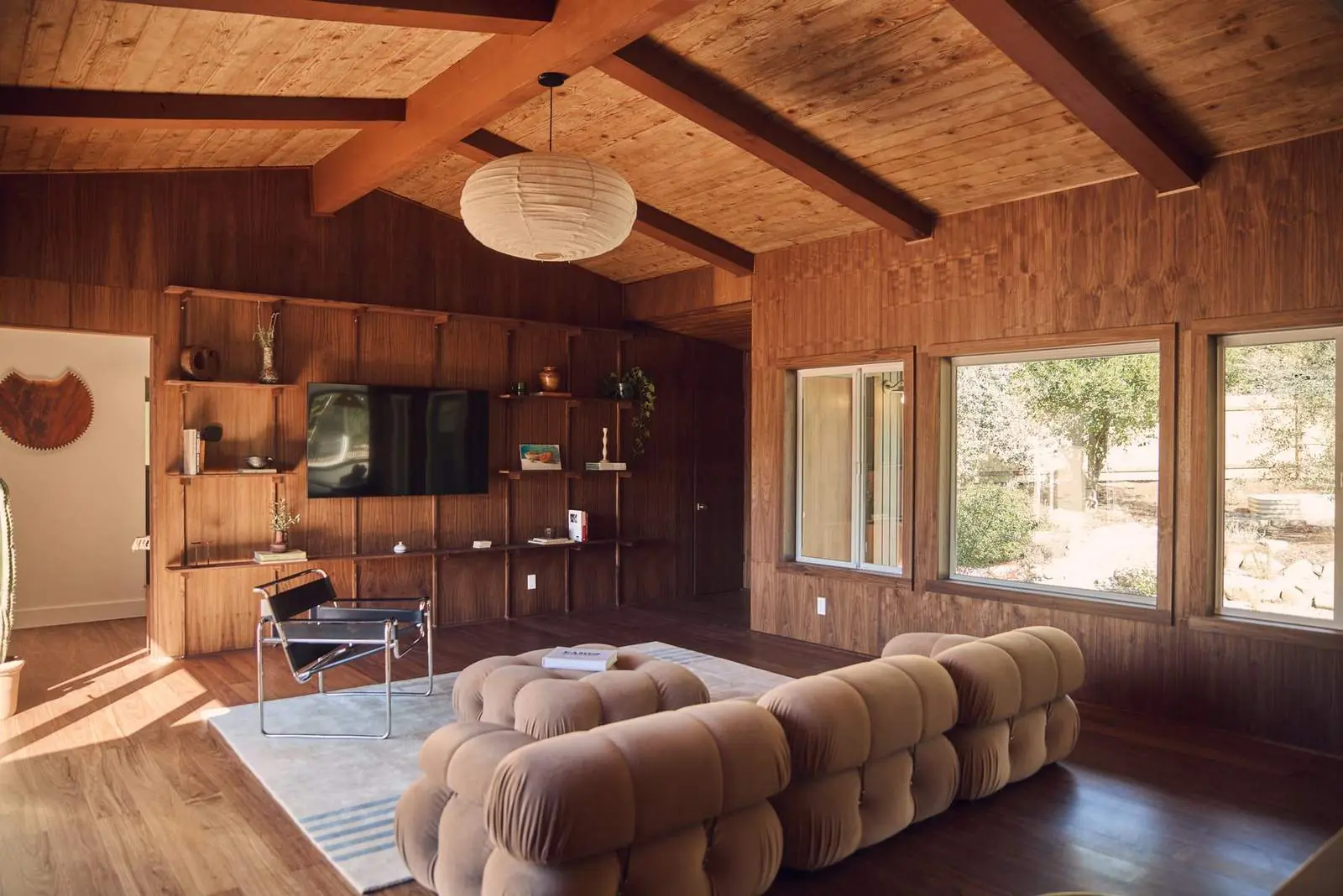 A living room with walnut paneling and built-in shelving under a beamed wood ceiling, Ojai East End