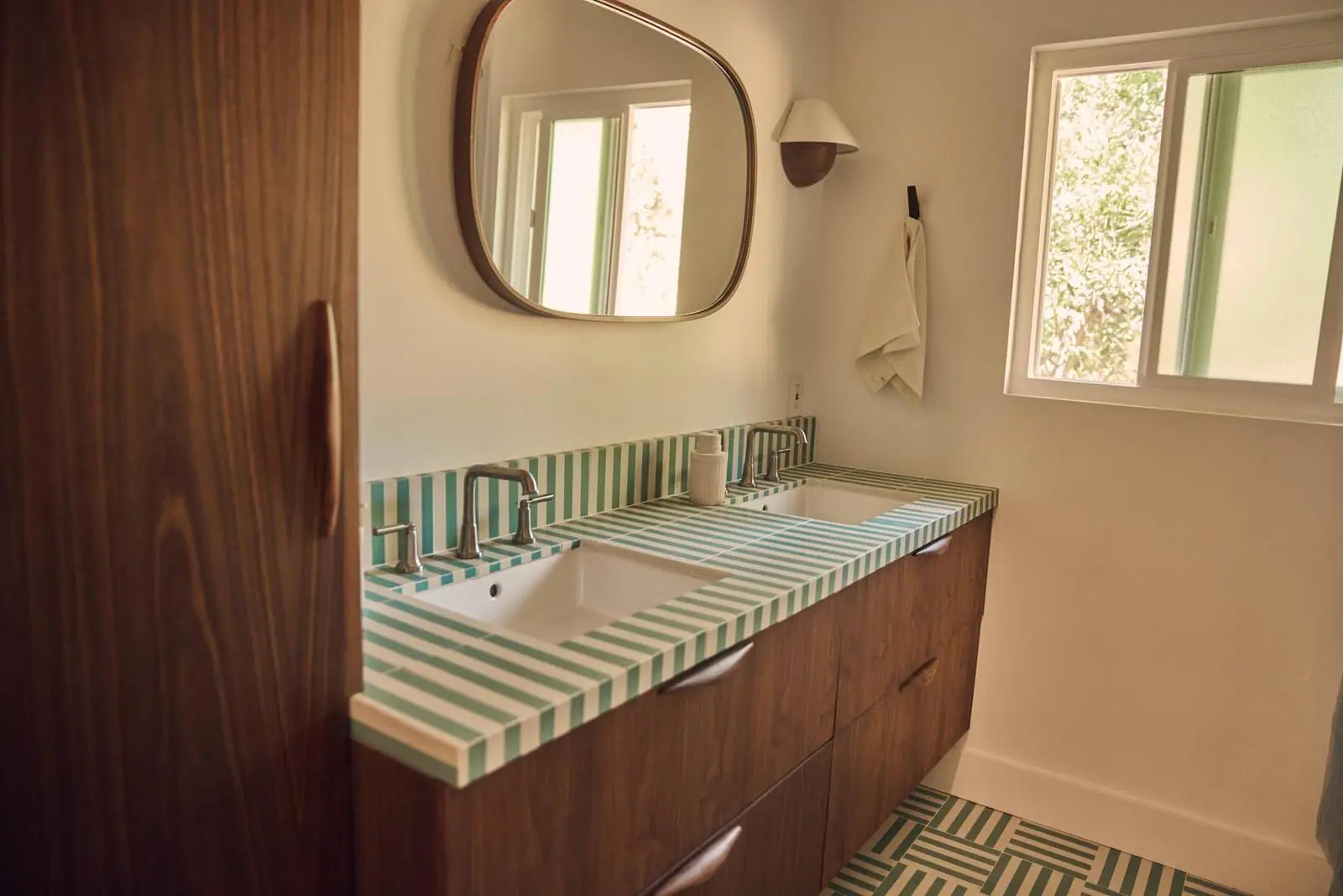 Bathroom vanity with striped green tile and a round mirror, Ojai East End