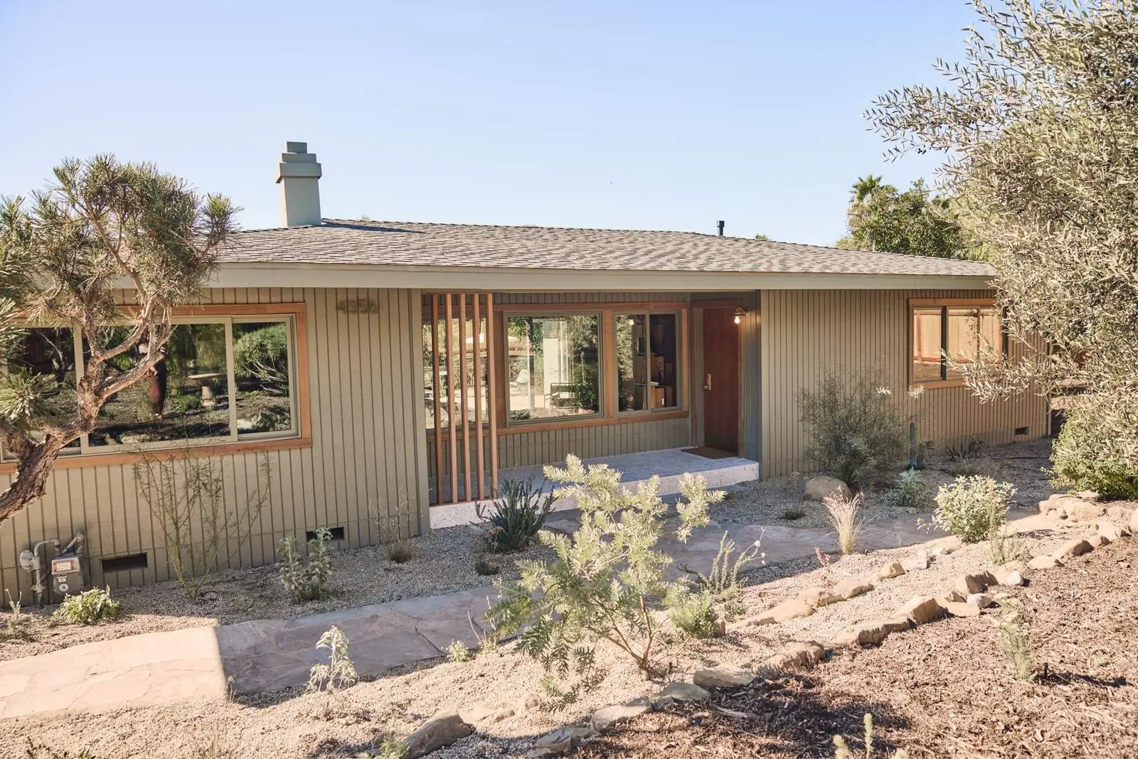 The front of a restored ranch house with board-and-batten siding and a dry garden, Ojai East End
