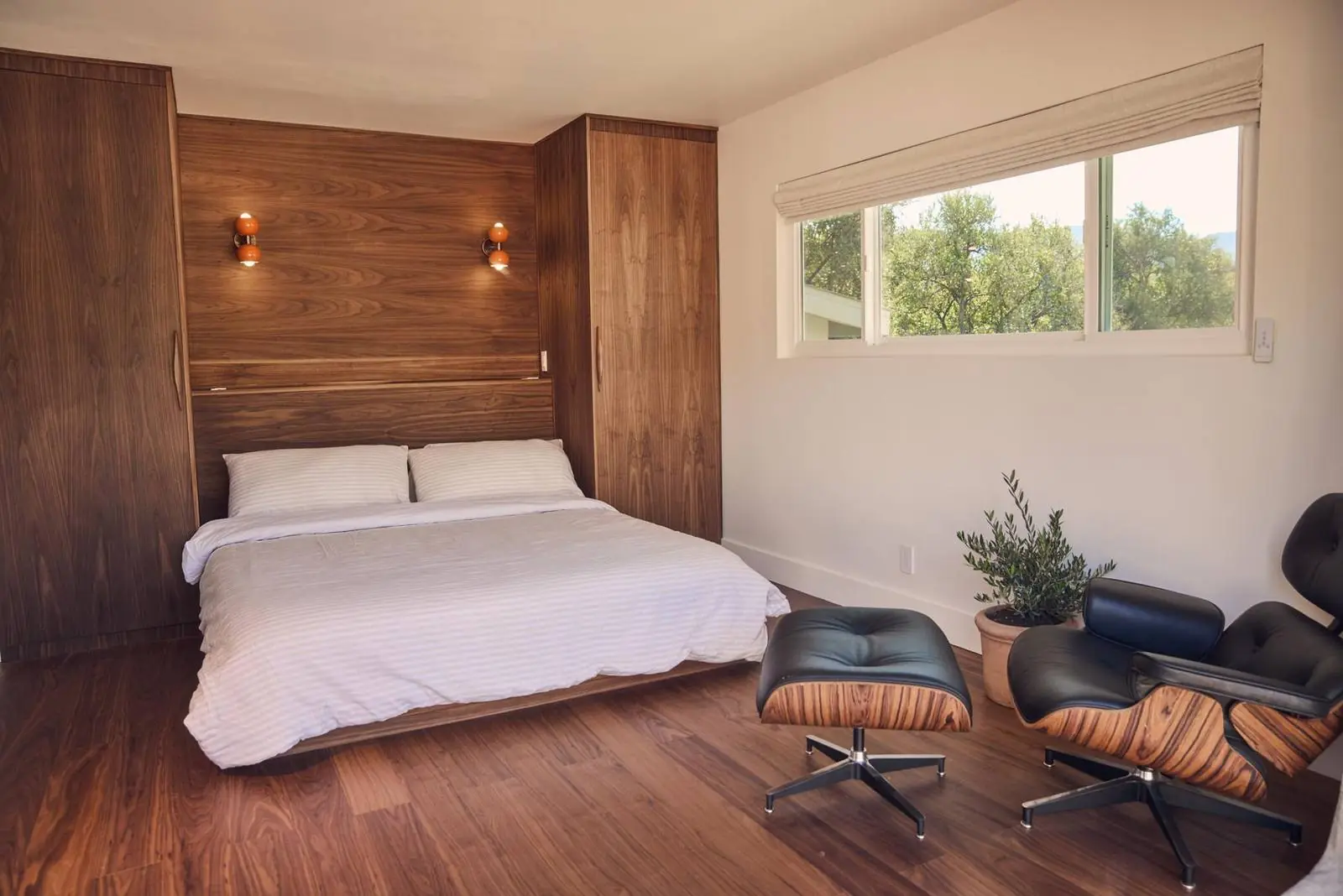 Bedroom with a walnut-paneled wall and a lounge chair, Ojai East End