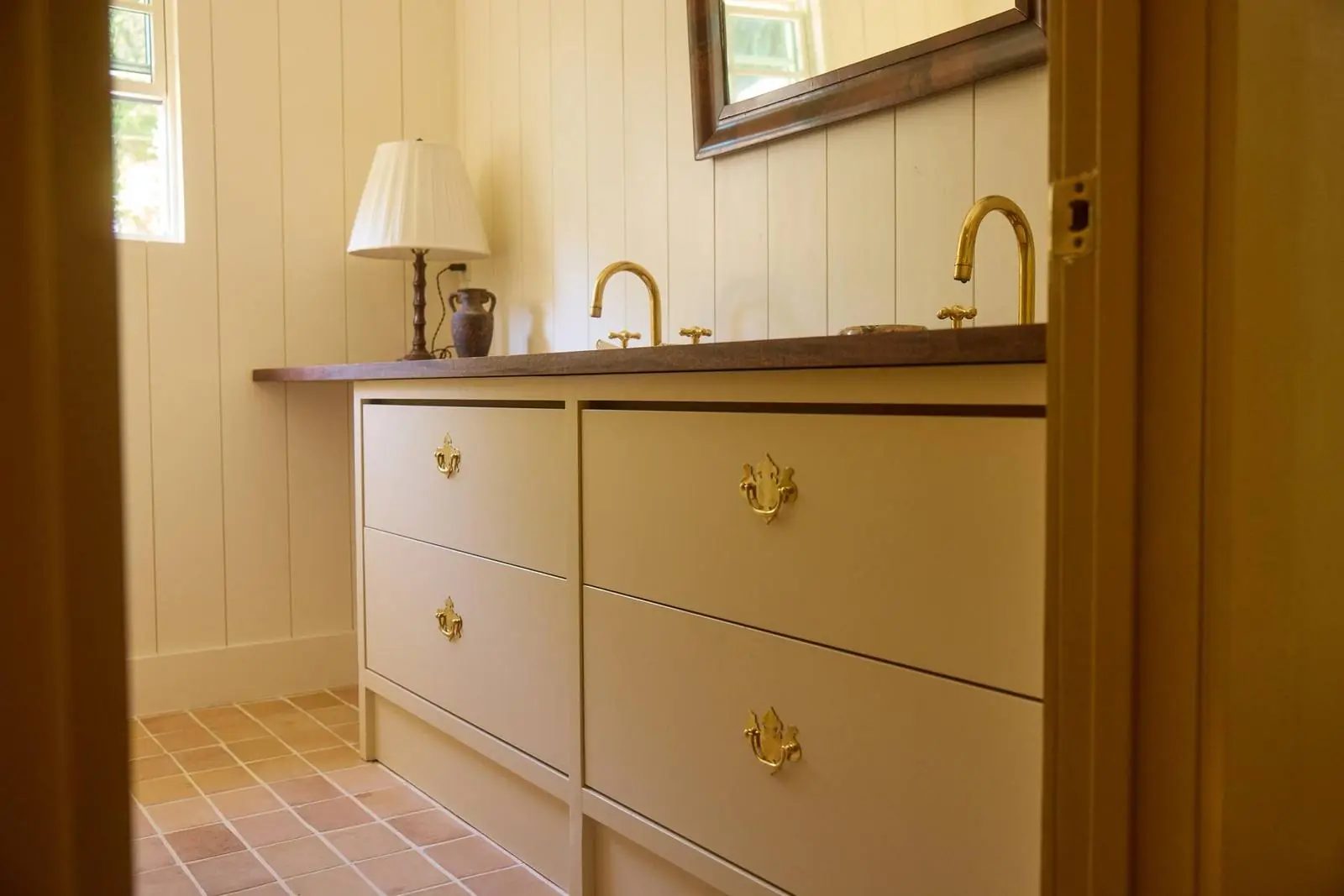 Bathroom vanity with brass faucets and a wood counter, Ojai Gridley