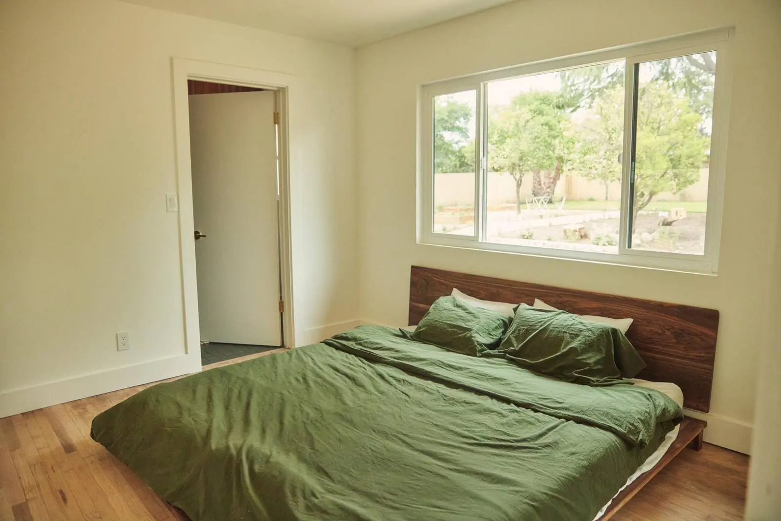 Bedroom with a low wood bed and green linen, Ojai Woodland