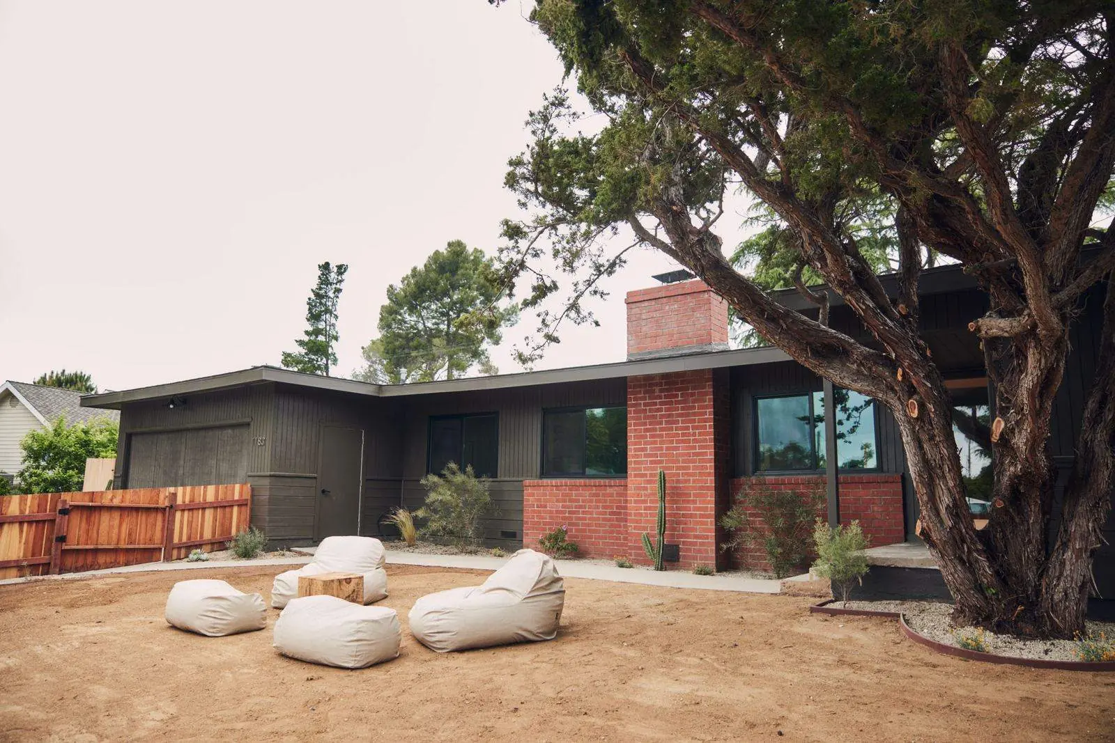 Ojai Woodland: a dark-sided ranch house with a red brick chimney under an old oak