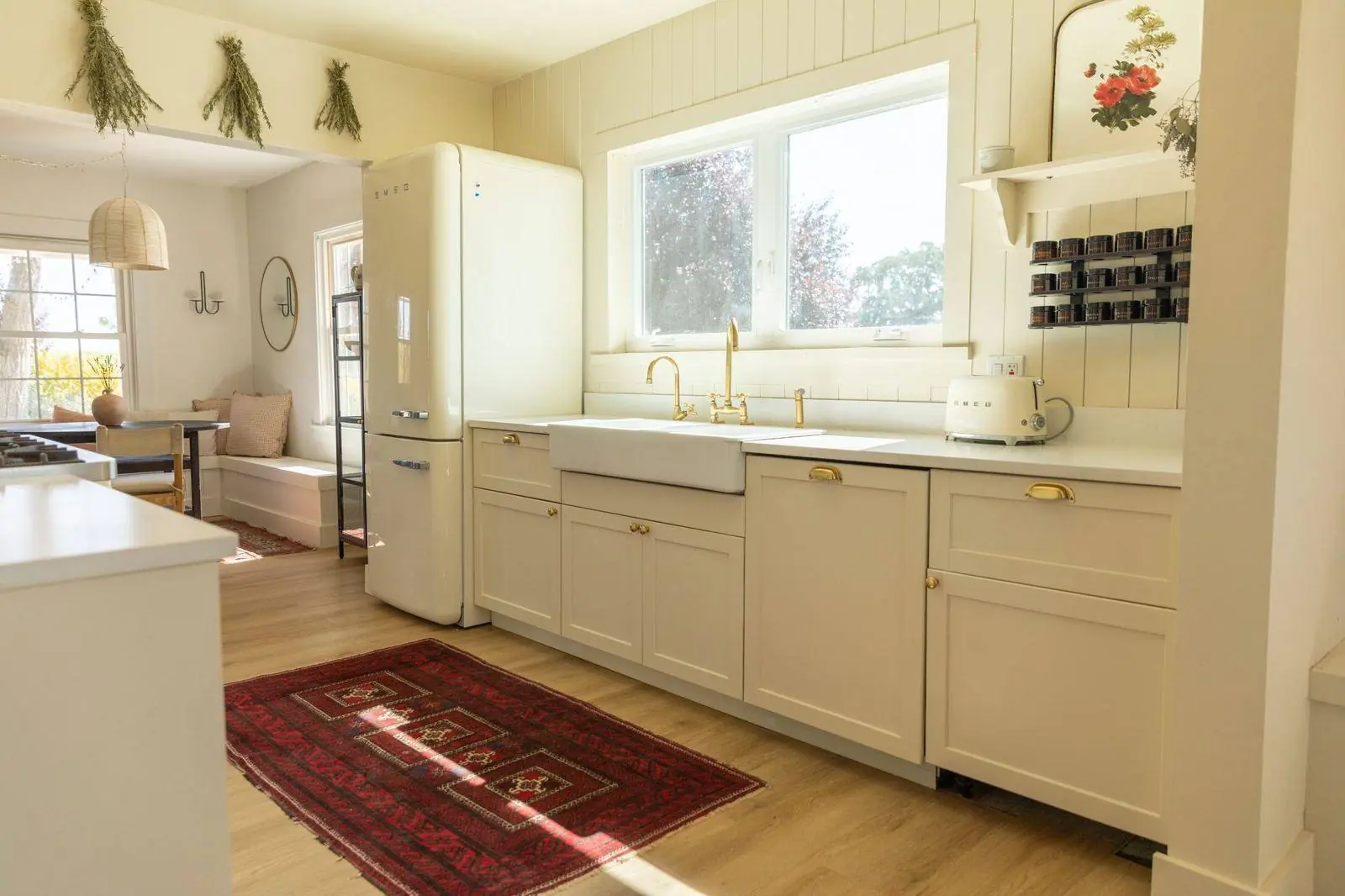 A cream painted kitchen with an apron sink and open window